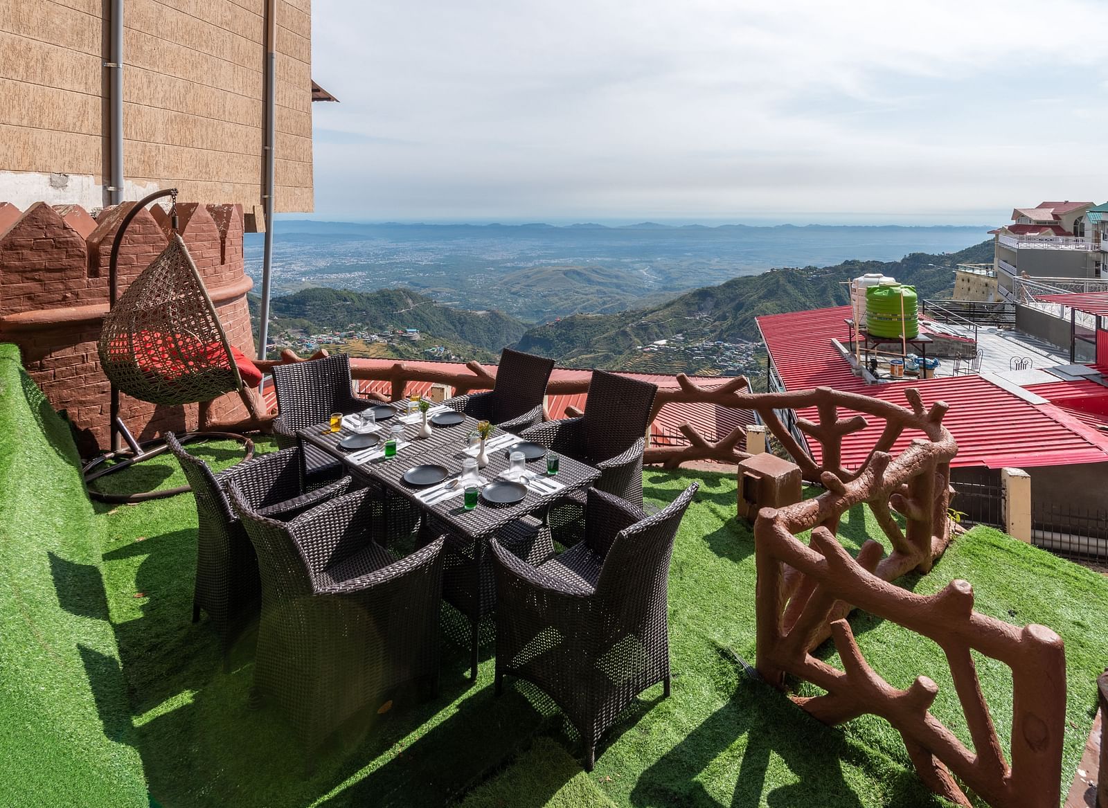 An outdoor dining area with a table and chairs set on a grassy terrace overlooking a scenic mountain landscape | DLS The Pearl